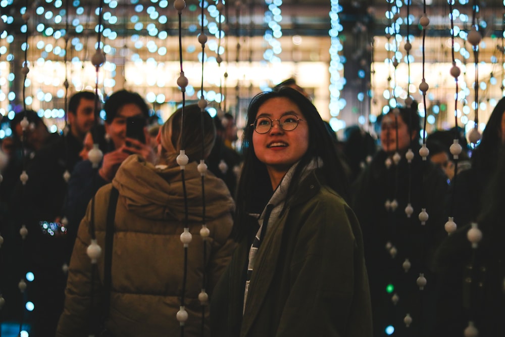woman wearing gray jacket surrounded by string lights