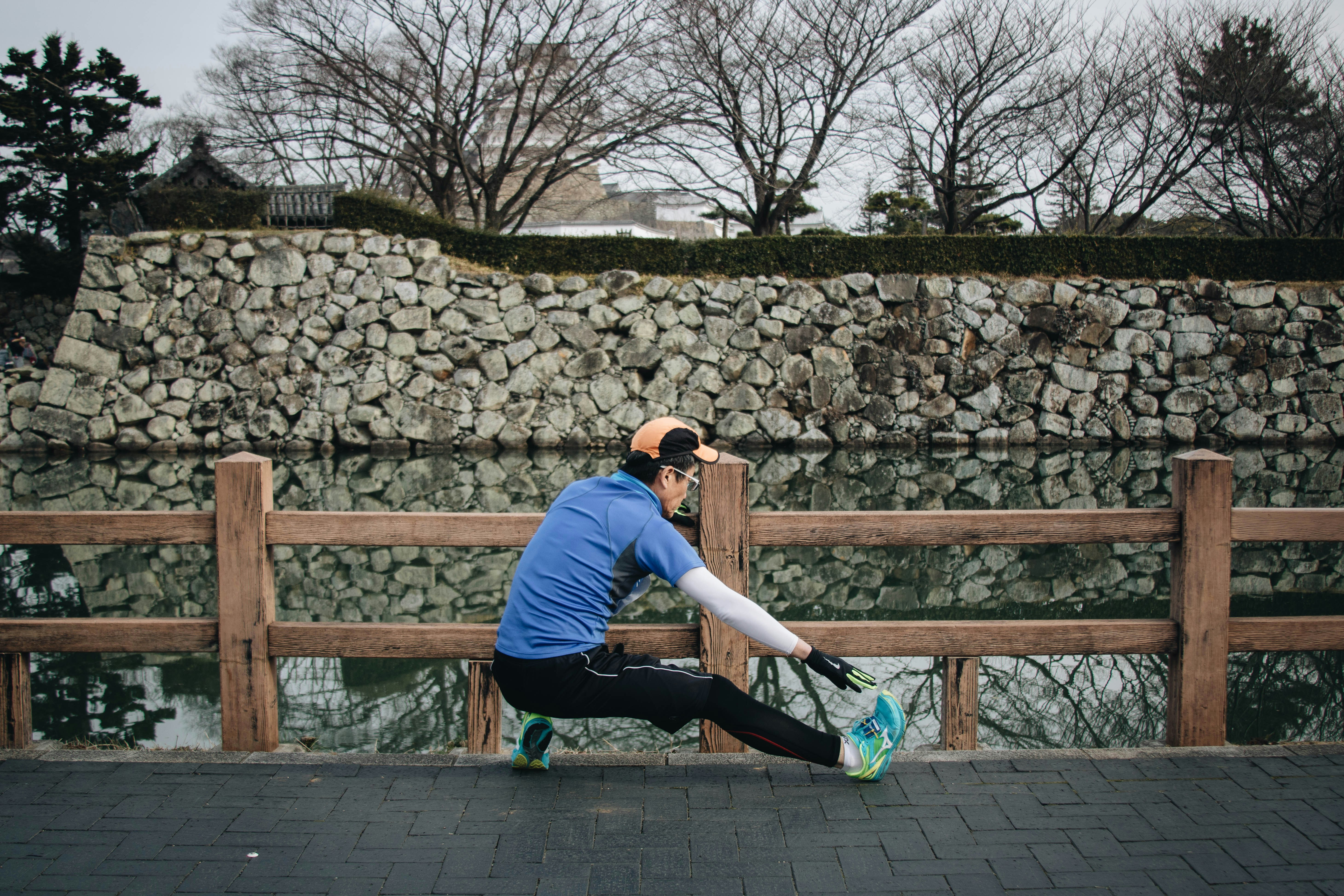 A beginner runner stretching on a bridge with nature on the background.