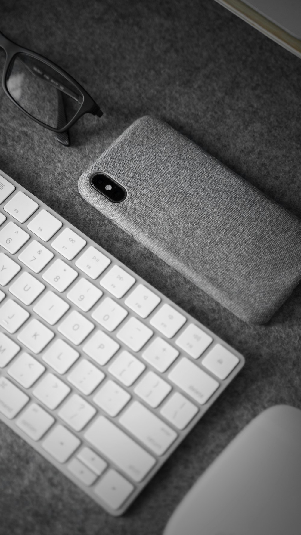 a computer keyboard, mouse, and glasses on a desk