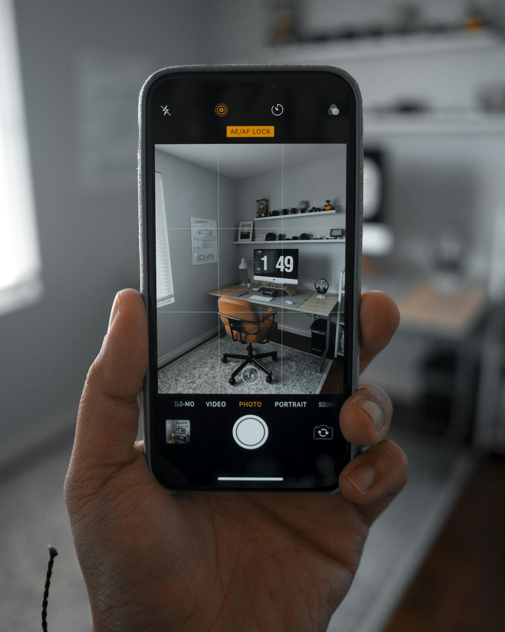 person using smartphone taking a picture of chair beside desk