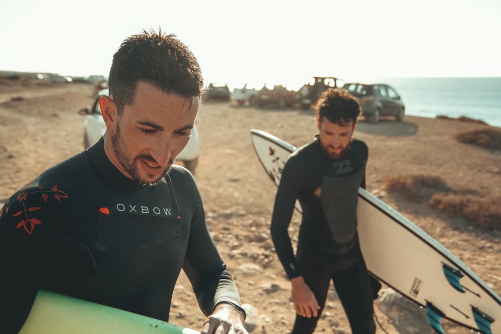 2 Männer mit Surfbrettern am Strand
