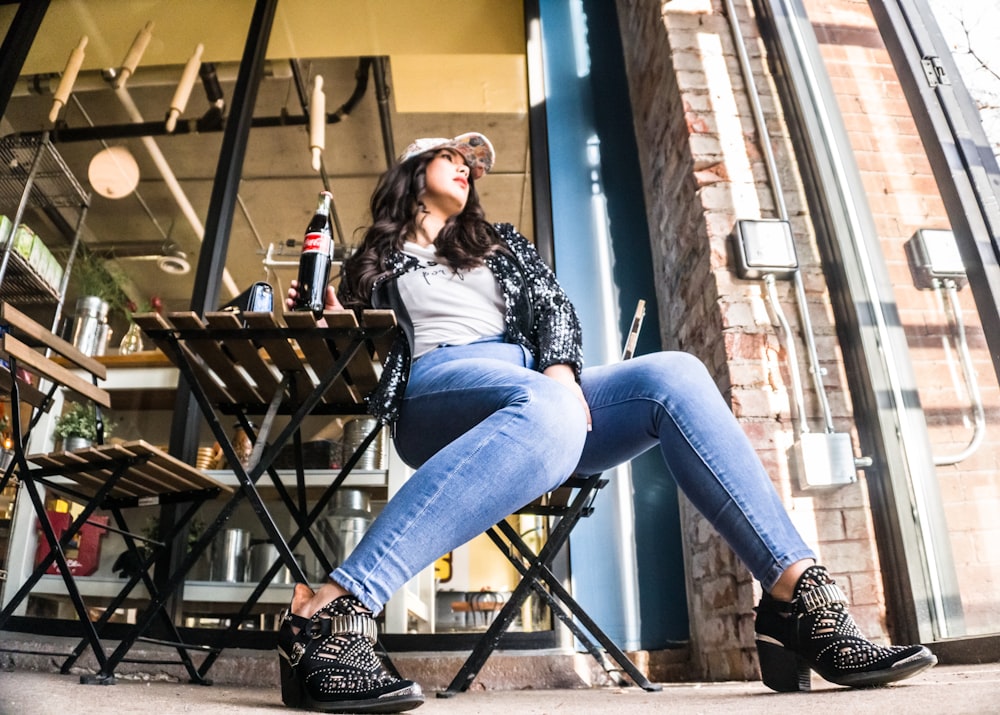 woman sitting on chair with Coca-Cola bottle beside