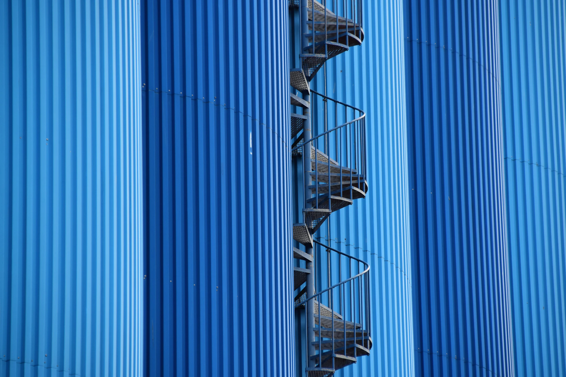a tall blue building with a spiral staircase