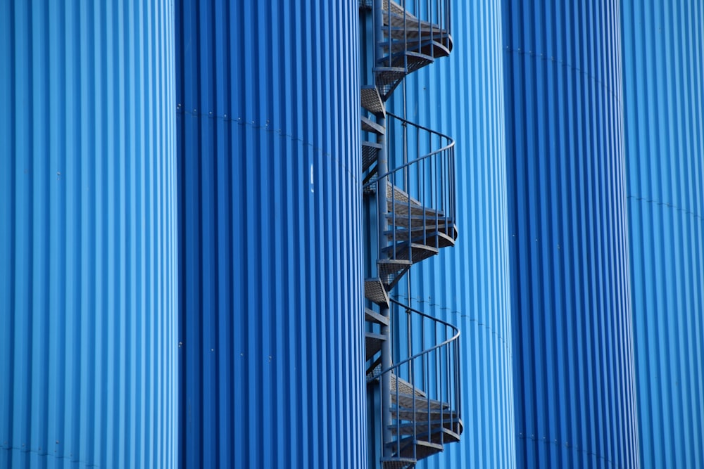 a tall blue building with a spiral staircase