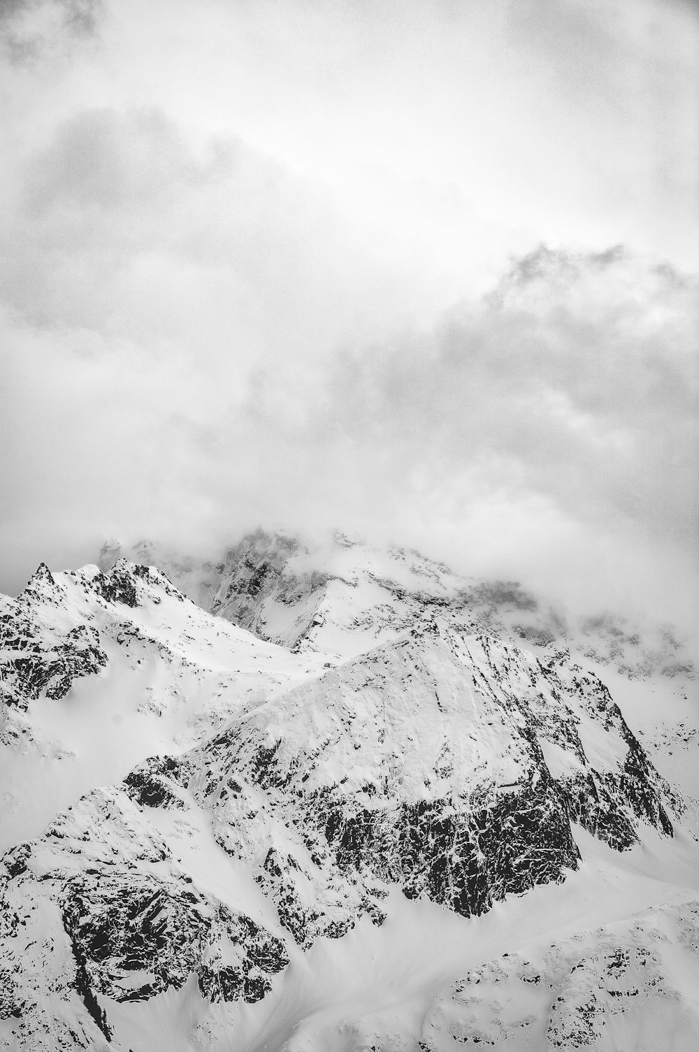 a black and white photo of snow covered mountains