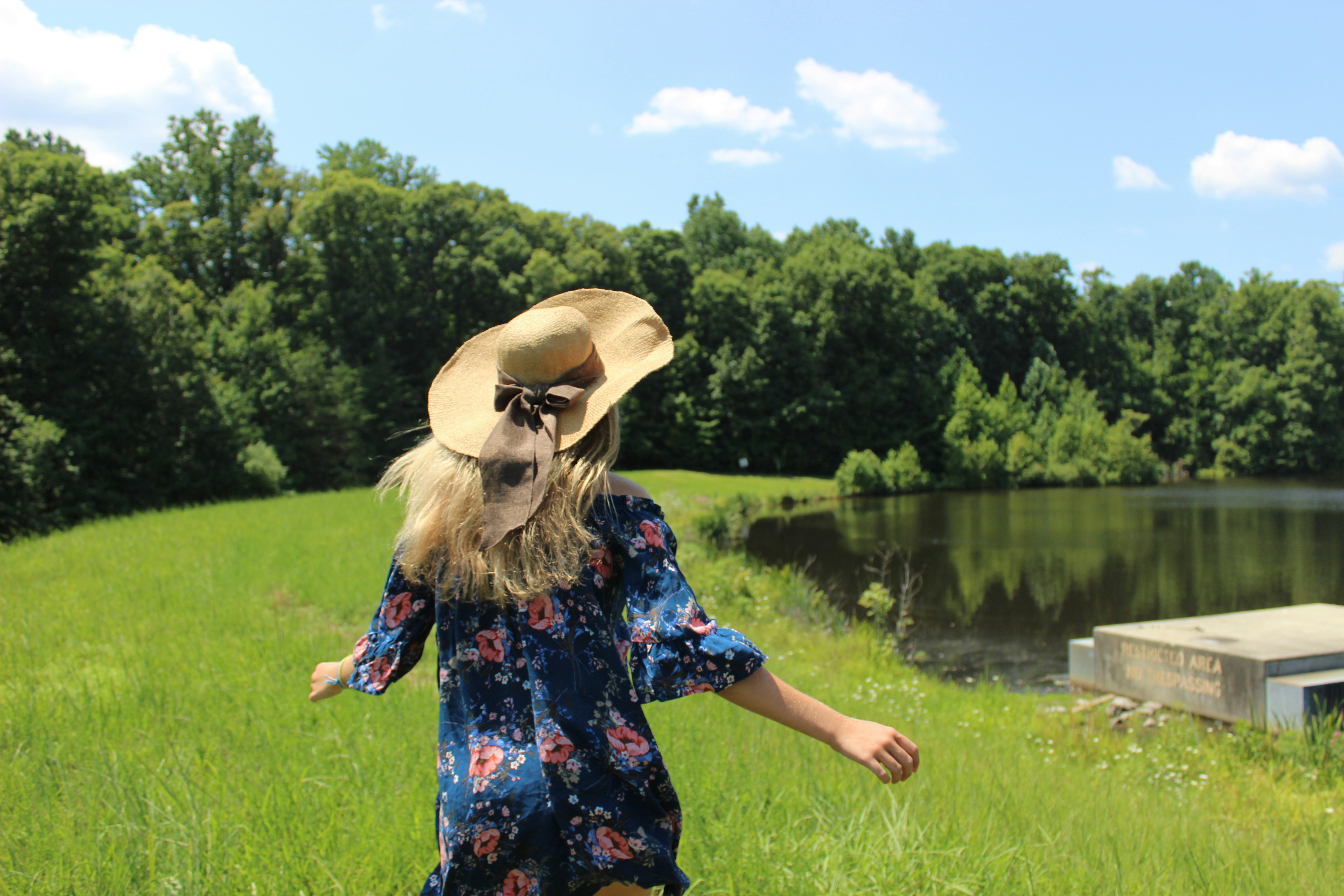 woman wearing sun hat walking towards dock