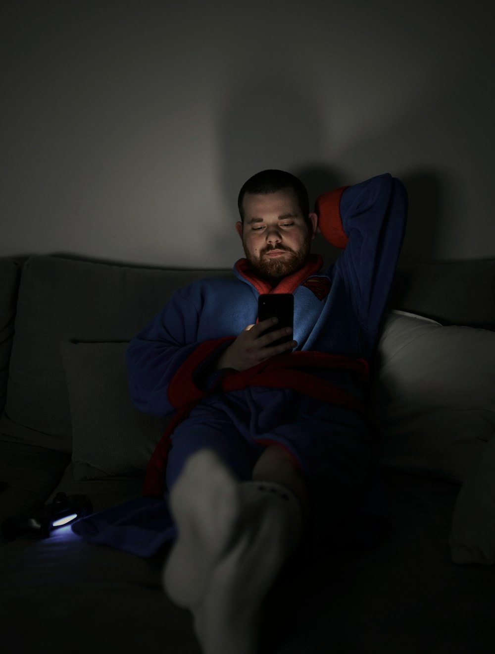 man sits on sofa while using smartphone