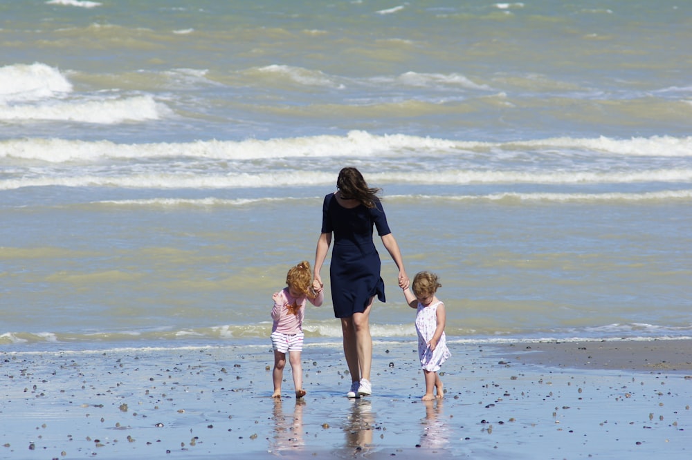 donna con 2 bambini che camminano sulla spiaggia