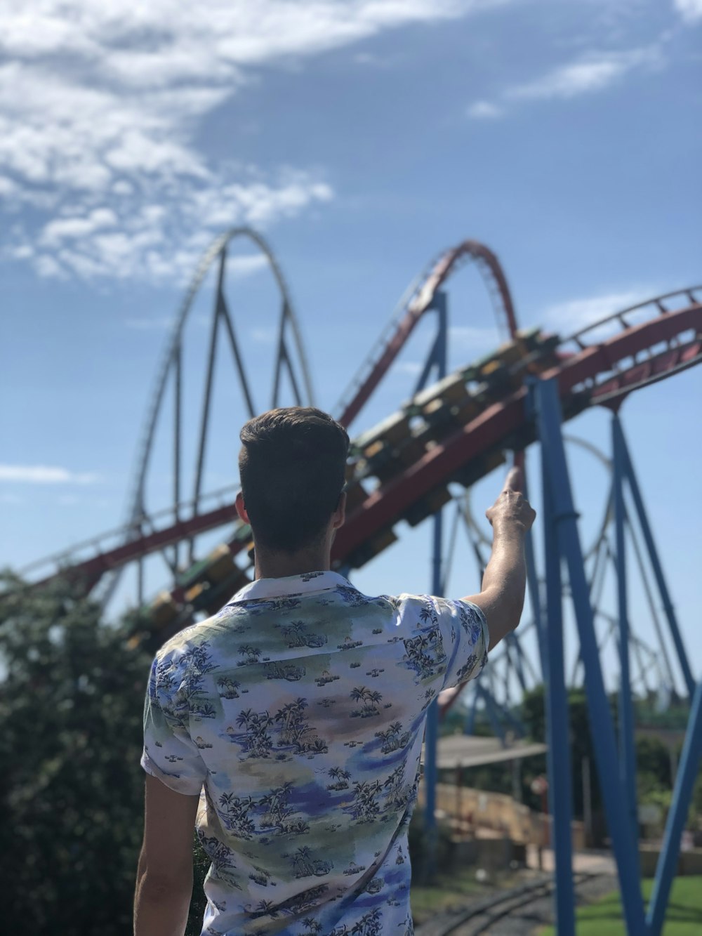 man wearing white polo shirt pointing on roller coaster