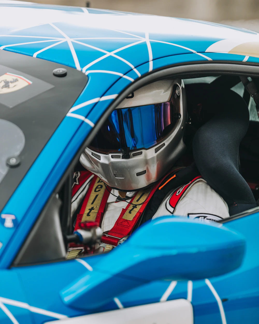 Driver strapped into a race car cockpit wearing a helmet