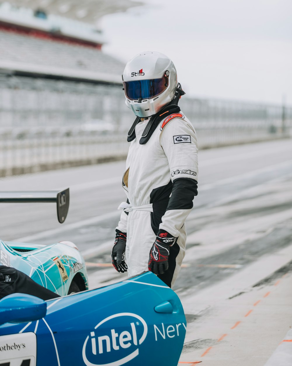 person in white white complete sports racing hears standing on race track during daytime