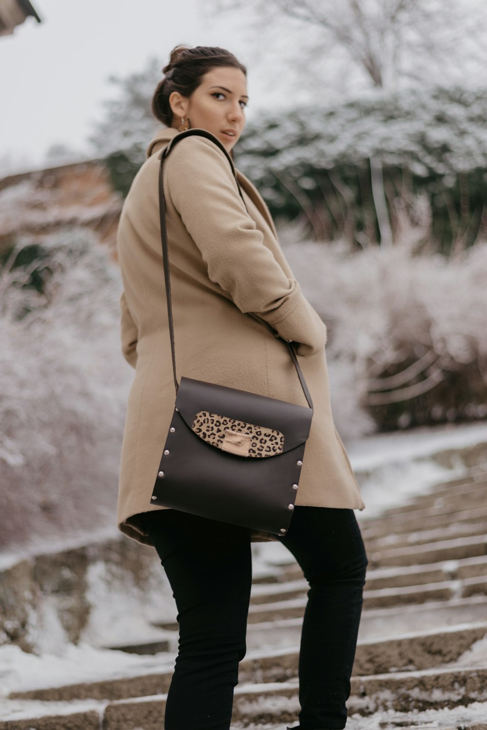 woman wearing brown coat walking near trees