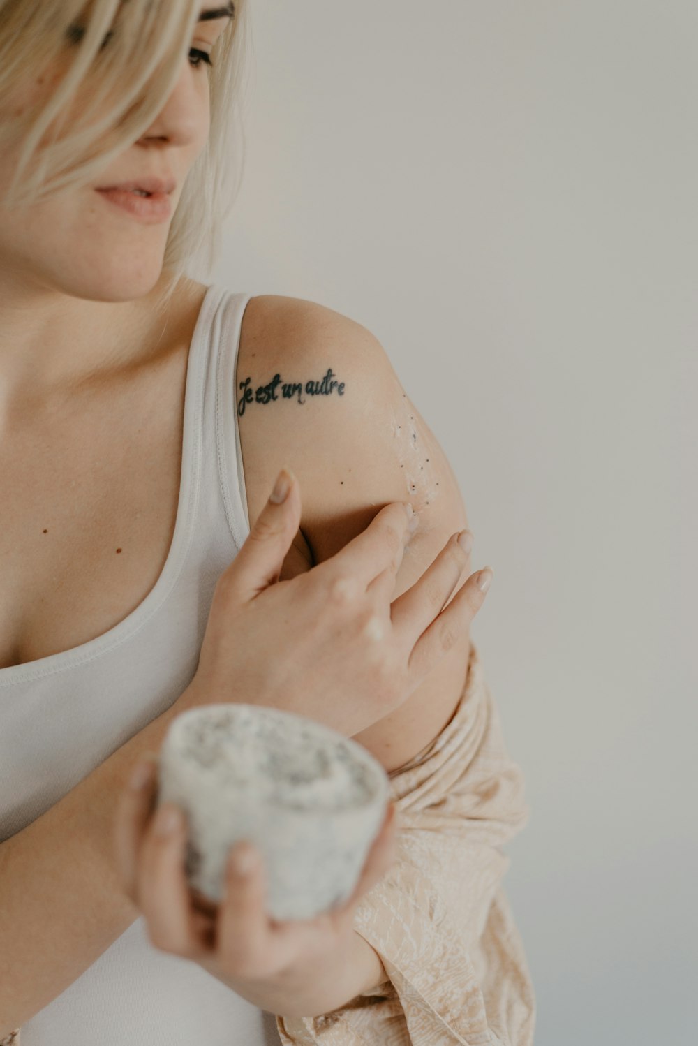 woman wearing white tank top while holding gray orgnament