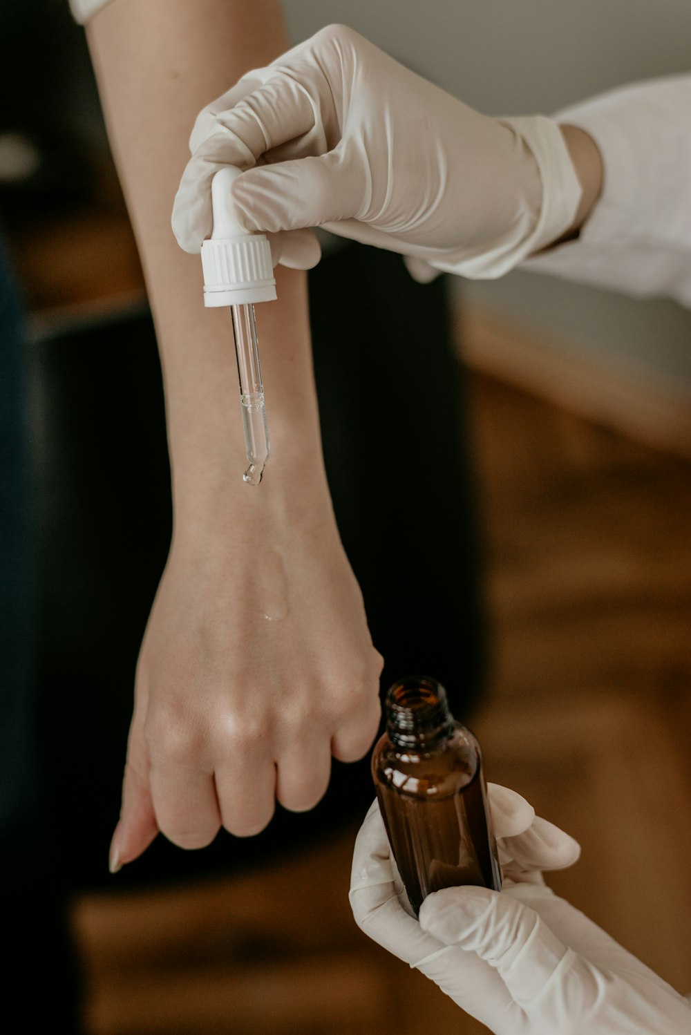 Persona con guantes blancos sosteniendo una botella de gota apuntando a la mano de otra persona