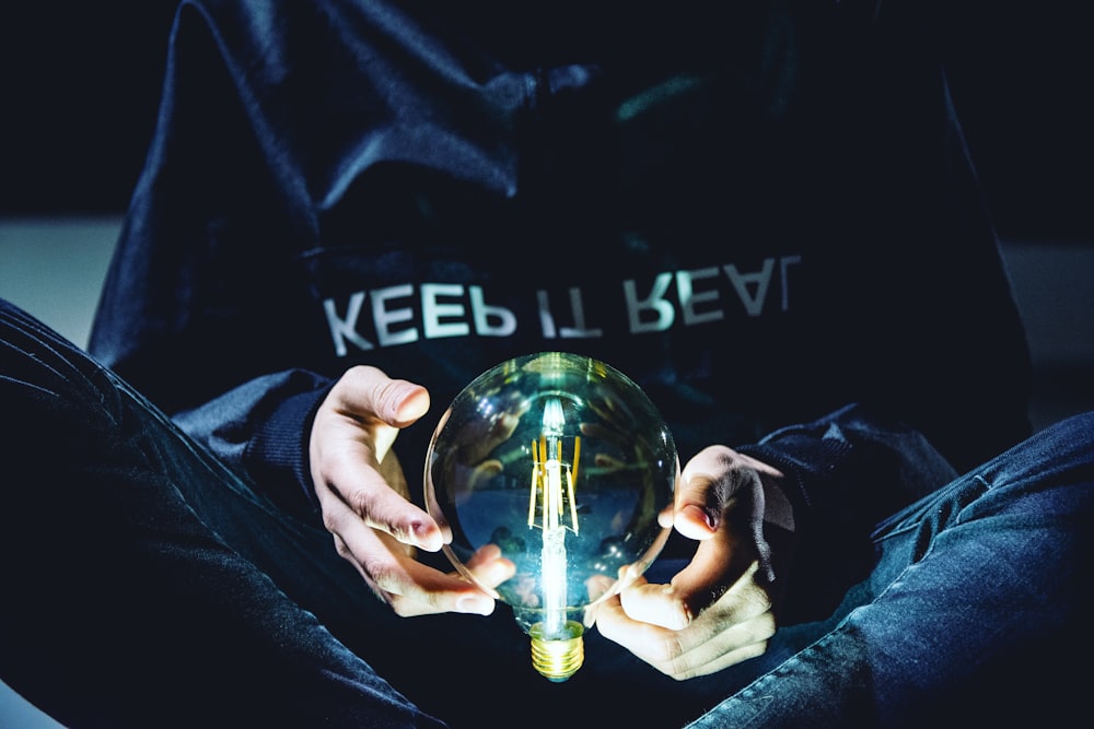 person holding clear glass light bulb