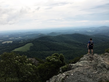 A winding mountain trail with a lone backpacker pausing to take in the vast landscape.