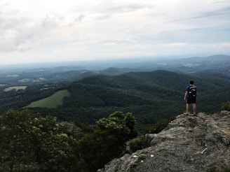 A winding mountain trail with a lone backpacker pausing to take in the vast landscape.