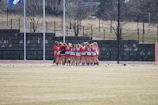 group of girls in white-and-red top hugging on field during daytime