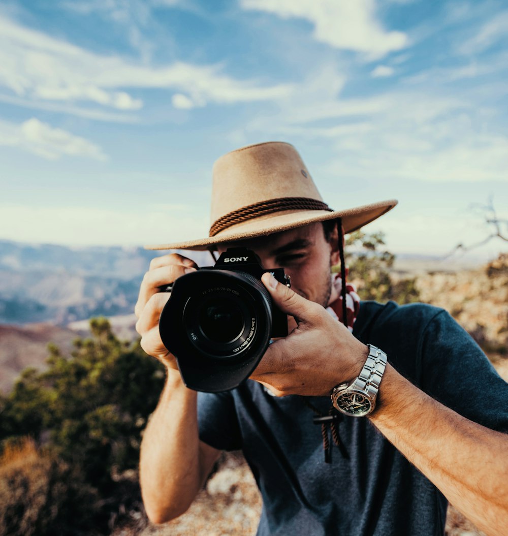 uomo che tiene la fotocamera DSLR