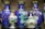 A collection of intricately designed ceramic vases and a lidded pot are displayed together. The vases mostly feature a vibrant blue background adorned with colorful floral patterns, including blossoms in white, pink, and orange hues. The lidded pot is smaller, showcasing ornate details with gold accents and floral designs.