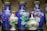 A collection of intricately designed ceramic vases and a lidded pot are displayed together. The vases mostly feature a vibrant blue background adorned with colorful floral patterns, including blossoms in white, pink, and orange hues. The lidded pot is smaller, showcasing ornate details with gold accents and floral designs.