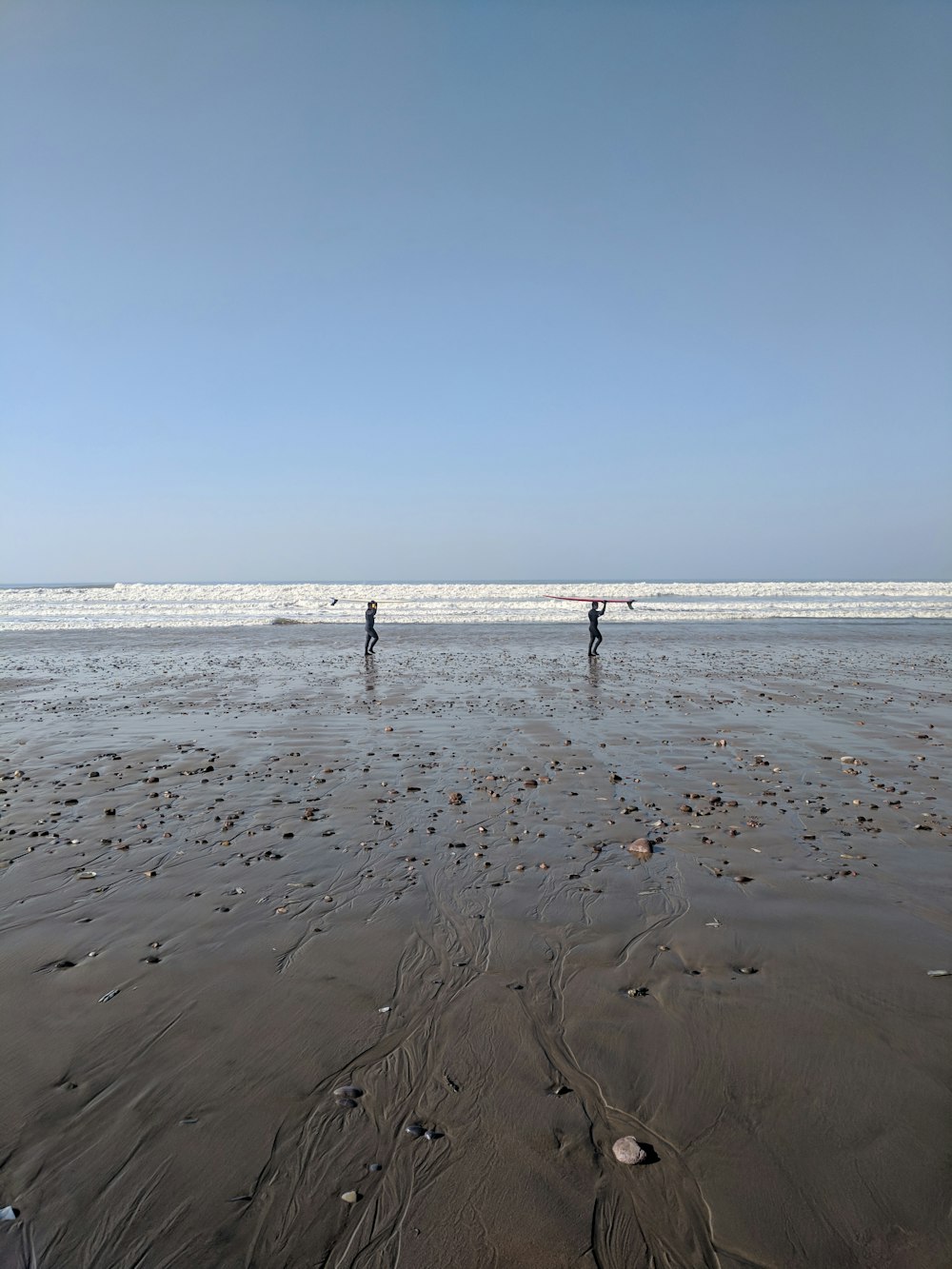 two person walking on seashore during daytime