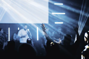 Fans raising their hands and singing along in a dimly lit underground venue