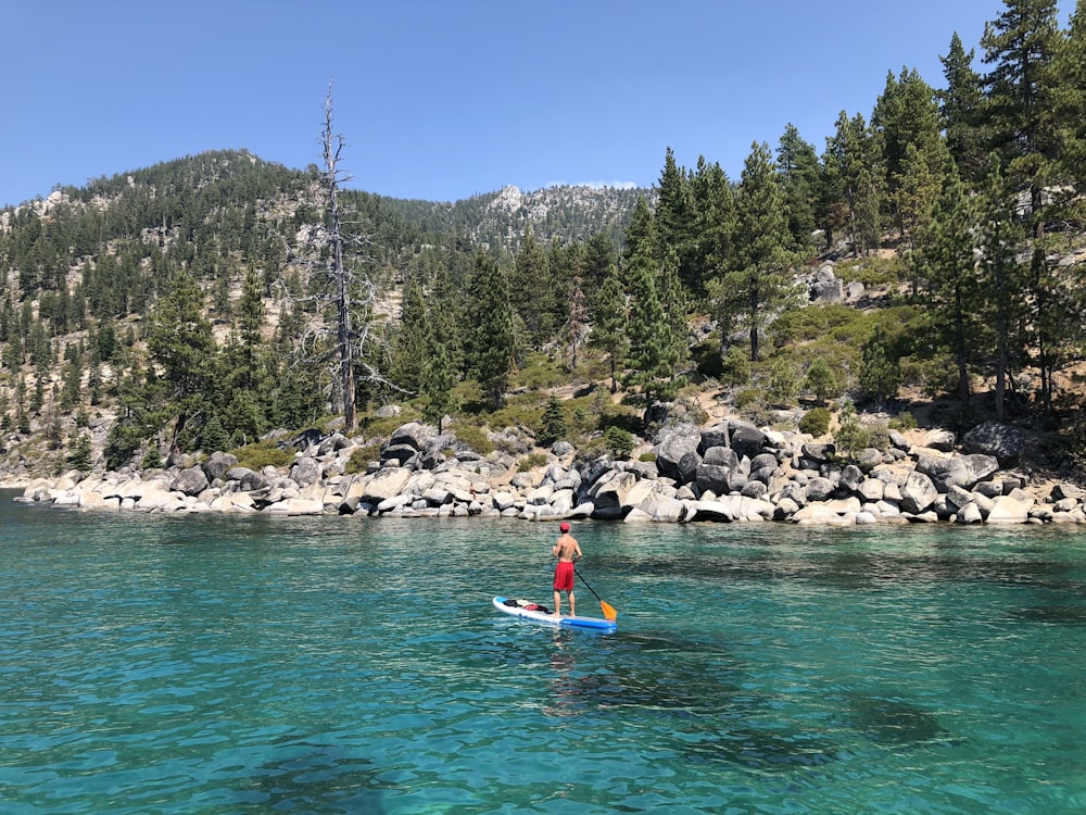 man standing on surfboard at sea during daytime