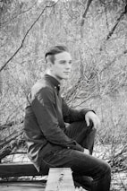 A contemplative teen sitting on a bench outdoors, lost in thought.