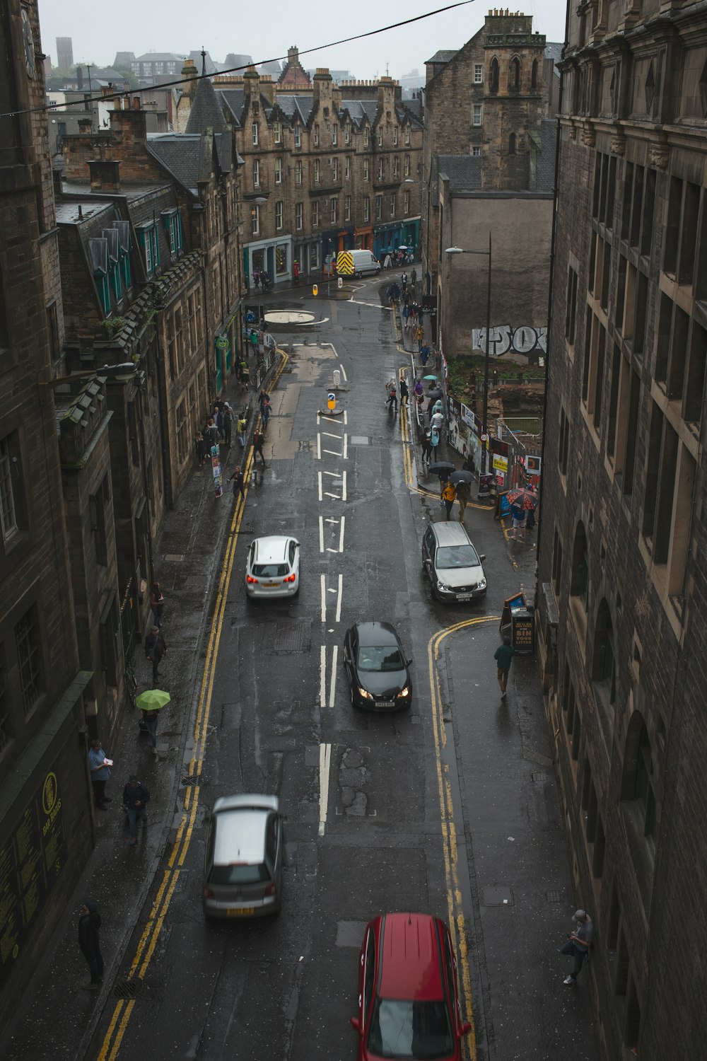 vehicles traveling on street in between buildings during daytime