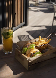 Overhead shot of a tray with several Rokko Burgers, fries, and a glass of soda with orange accents