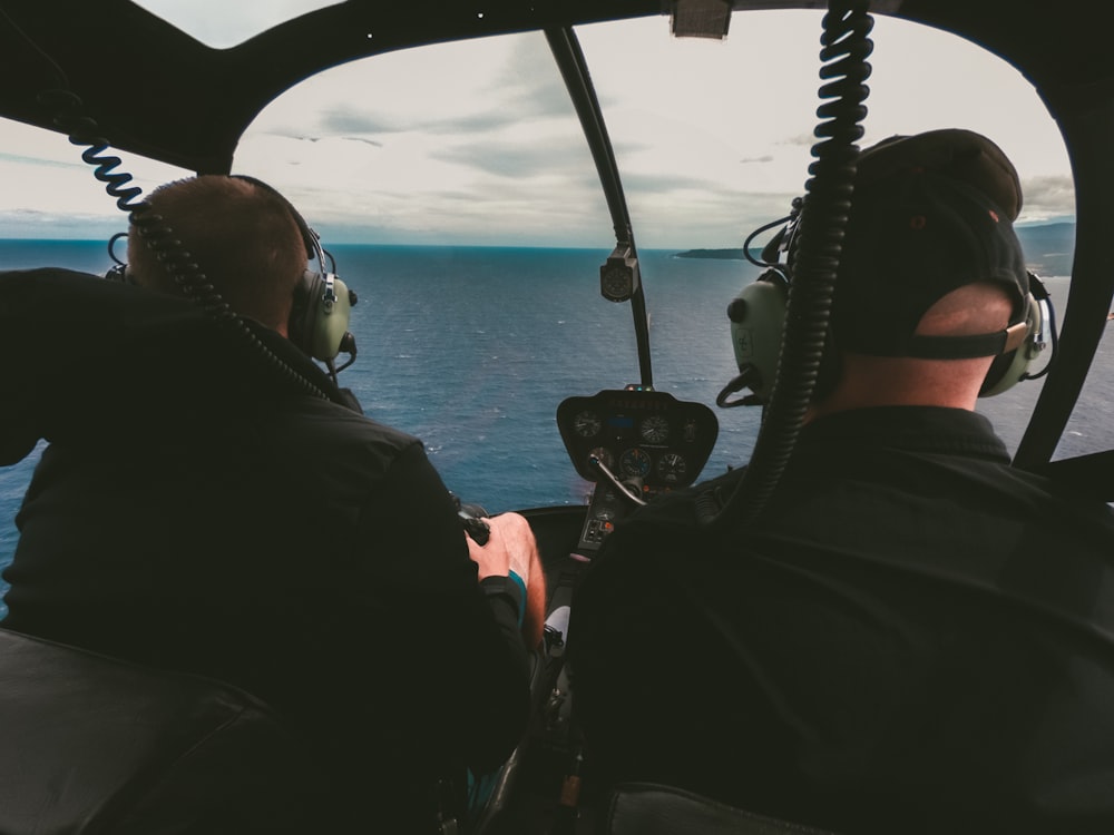 two men in helicopter above sea