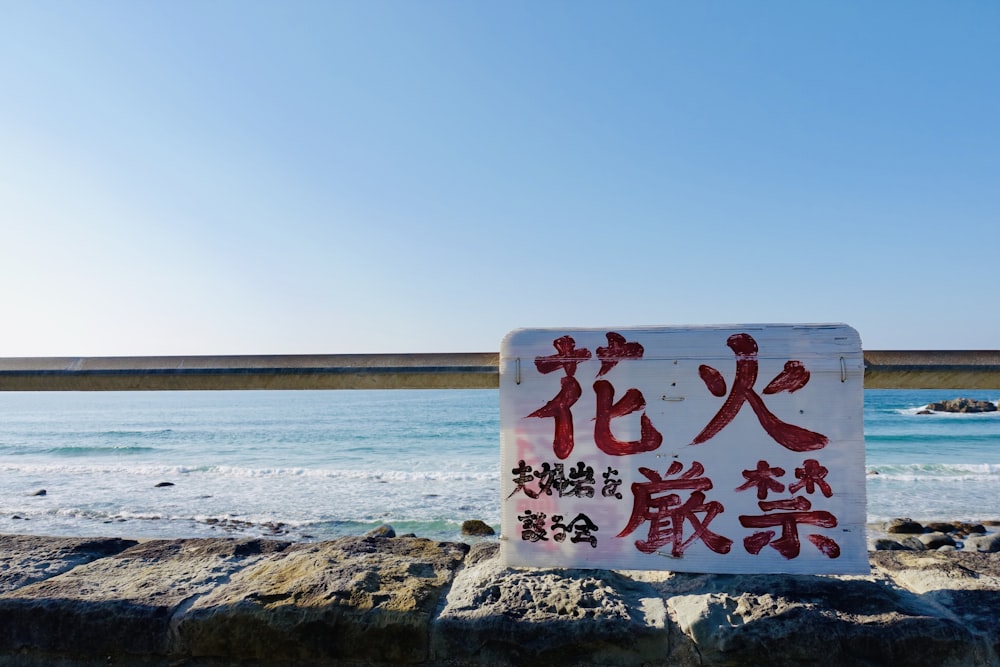 a sign on a rock near the ocean