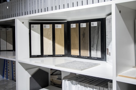 Several wood samples displayed on a white shelf, each with a different wood color and texture. Surrounding these samples are various design catalogs and color swatches.