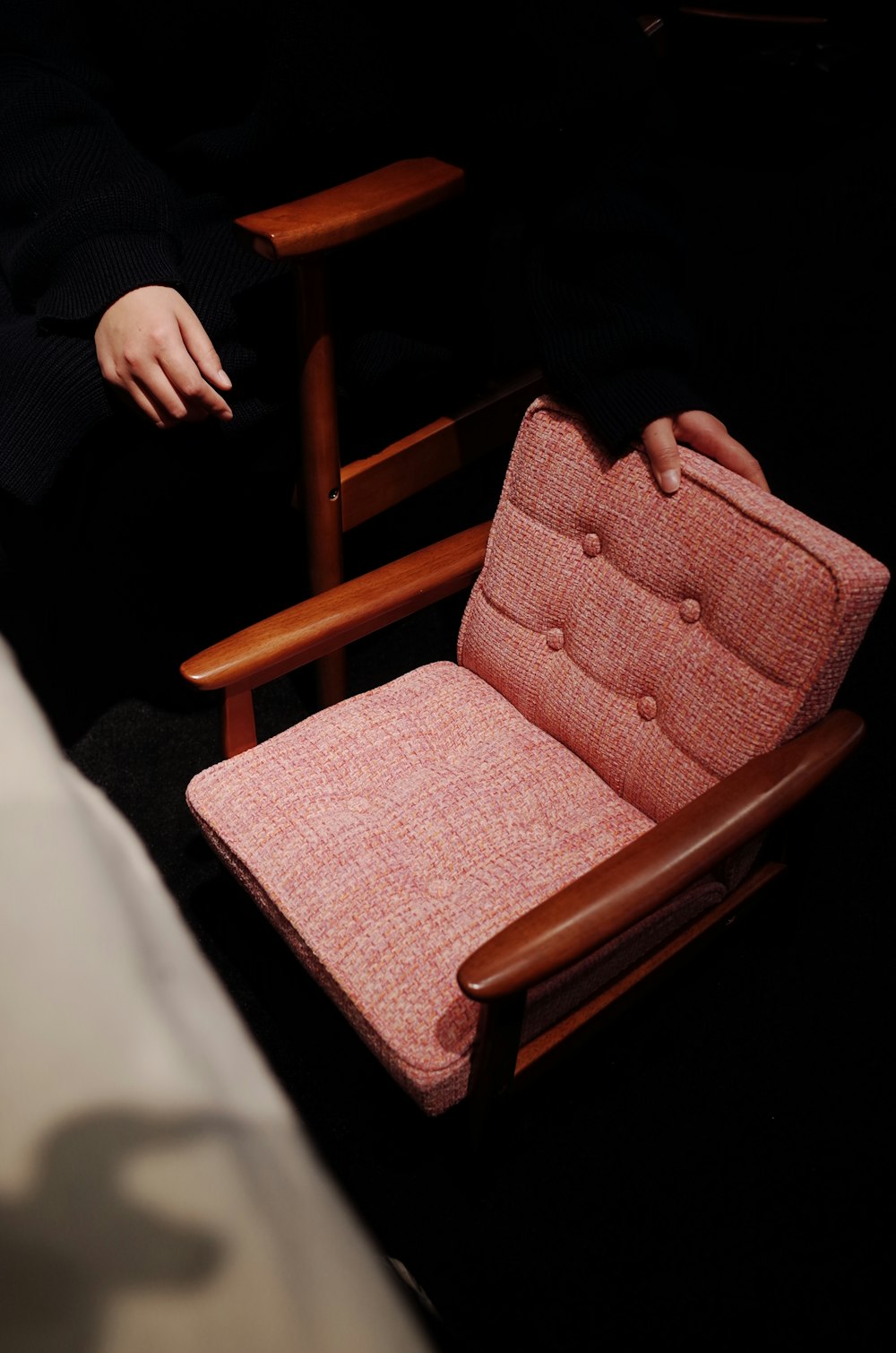 person touching brown wooden armchair