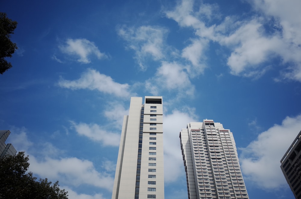 two grey high rise buildings under white cloudy sky