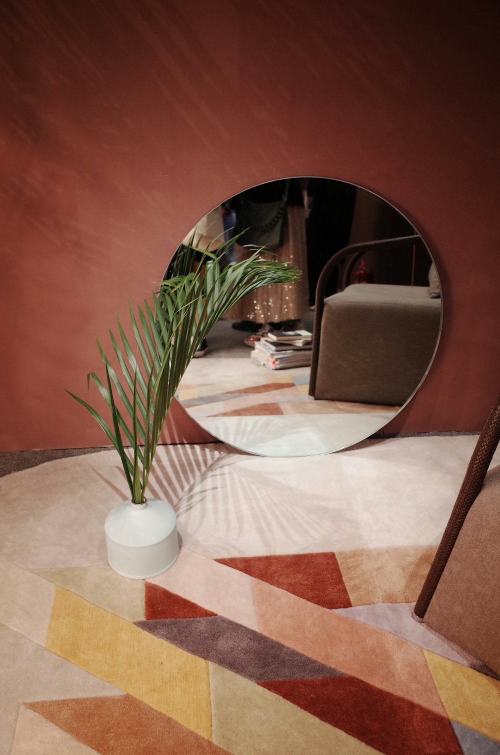 round mirror behind potted flower on floor inside room
