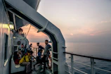 A group of sailors sharing a warm meal together on a ship deck at sunset.