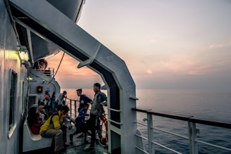 A diverse group of seafarers and consultants gathered on a ship deck, sharing smiles and stories under a clear blue sky.
