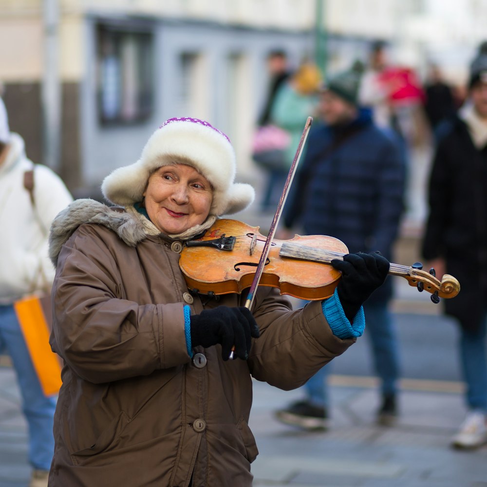 woman wearing brown coat playing violin