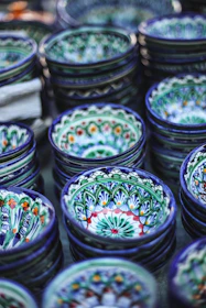 Close-up of colorful ceramic bowls stacked gently, showcasing rich glazes in blues, greens, and reds.