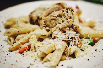 Close-up of a steaming plate of homemade pasta with fresh basil and grated pecorino cheese.
