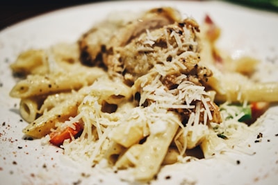 A close-up of a creamy pasta dish topped with herbs and grated cheese.