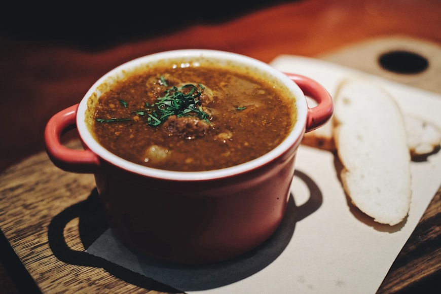 Hungarian goulash soup with bread in a classic red pot