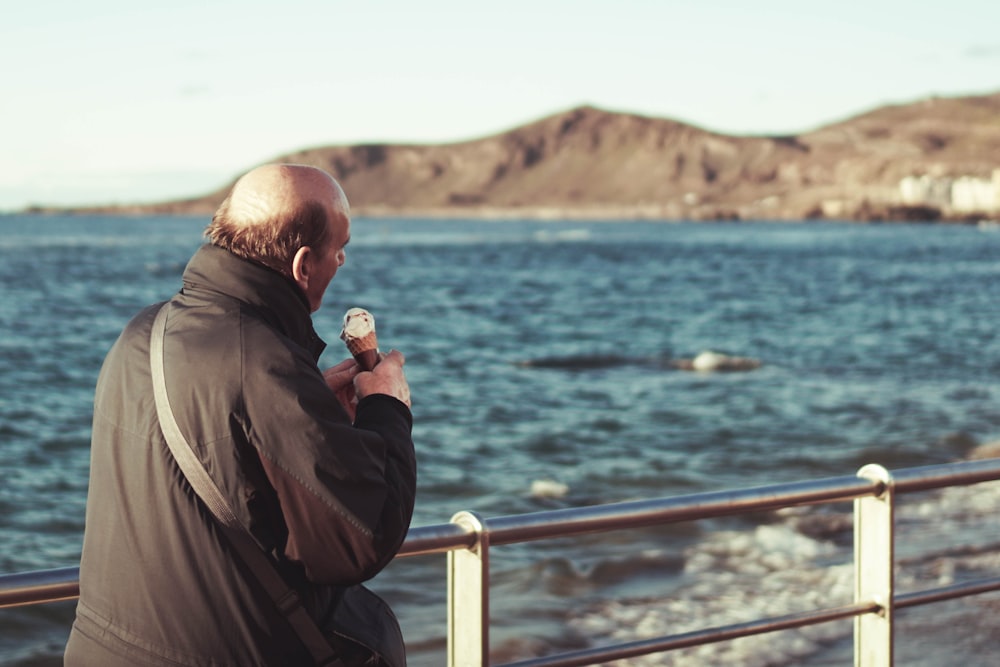 man wearing black jacket eating ice cream