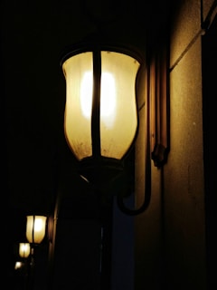 Close-up of a handcrafted bamboo wall lantern glowing softly against a textured wall.