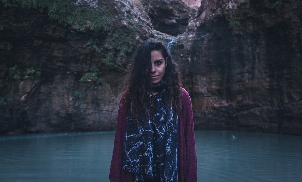 woman wearing black and white inner shirt with maroon cardigan standing near body of water