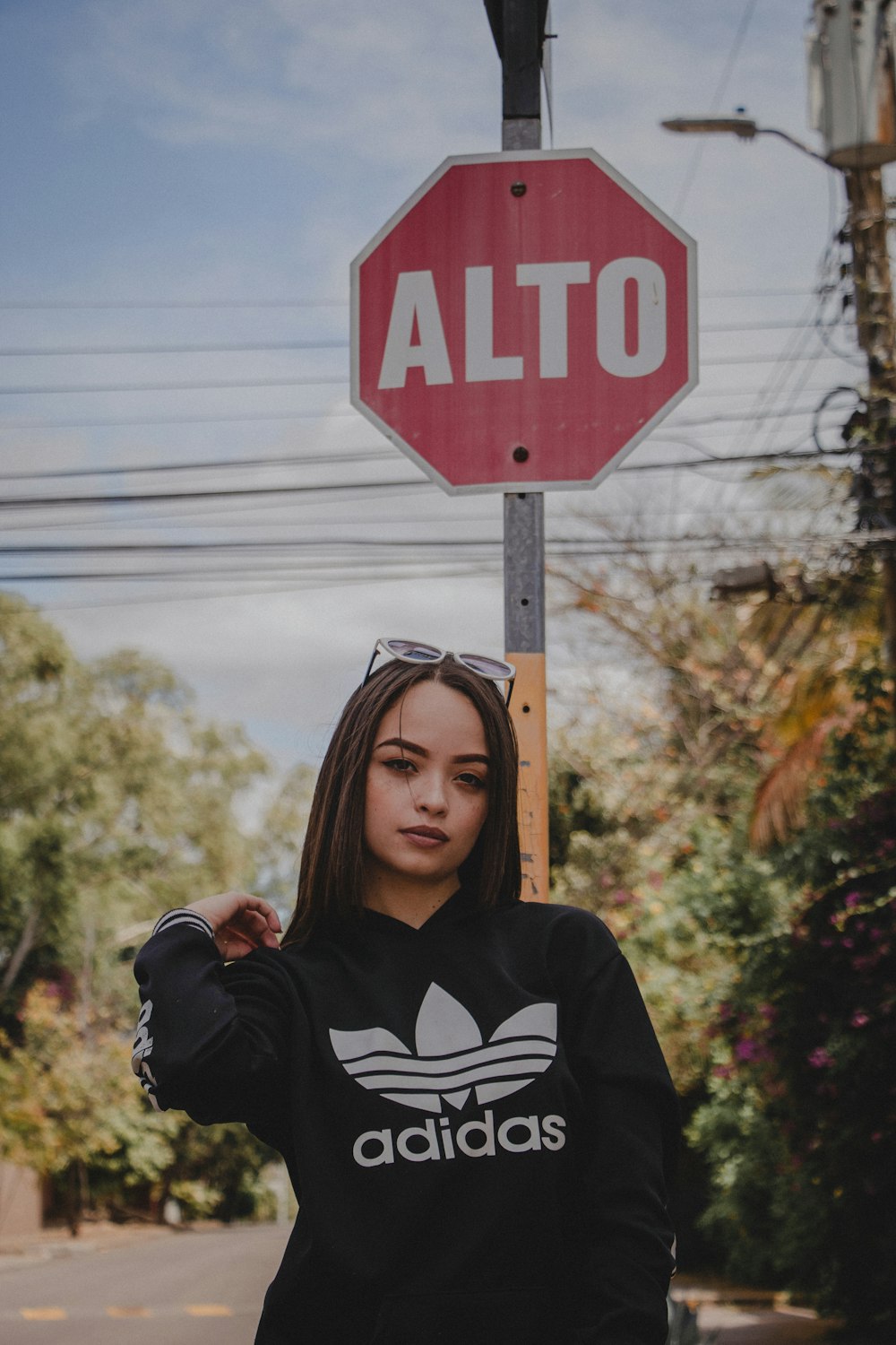 woman wearing black adidas hoodie near stop signage during daytime