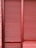 Red metal shutters with horizontal ridges are framed by red and pink brick walls.
