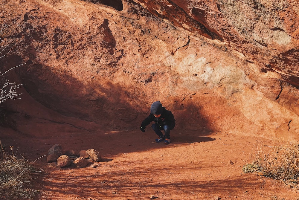 person wearing blue beanie across brown rocks